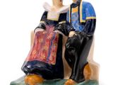 une figurine représentant un homme et une femme assis sur un banc