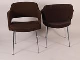 pair of brown chairs with chrome legs against a white wall