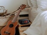 a small ukulee sitting on a bed next to a pillow