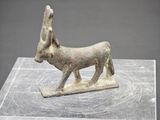 une ancienne figurine en bronze représentant un âne, posée sur un socle en marbre