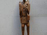 statue en bois représentant un homme tenant un couteau dans chaque main