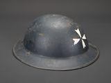 an old helmet with a cross painted on it sitting on a table