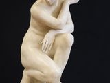 statue of a woman sitting on a pedestal with her hands on her knees