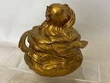 brass figurine of a woman holding a bowl with a fish on it
