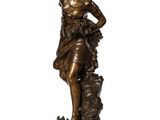 a bronze statue of a woman standing on a rock with her hands on her head