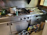 a kitchen with a stove and a lot of clutter on the floor
