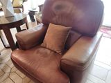 a brown leather chair and a table in a living room