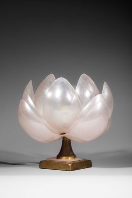 a white glass flower on a gold stand on a gray background