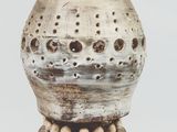 a white vase with holes in it on a table