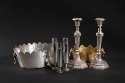 several silver candlesticks and a silver bowl on a black background