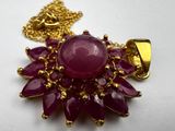 necklace with a red stone surrounded by gold chains on a white surface
