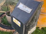 a black box sitting in the grass next to a potted plant