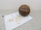 an old leather soccer ball sitting on top of a cloth bag