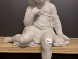 une petite statue représentant un enfant assis sur une étagère