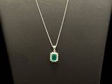 an emerald and diamond pendant on a mannequin necklace