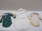 trois vêtements de bébé posés sur une table blanche