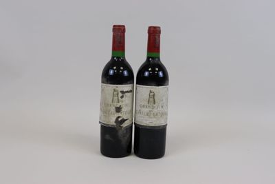 two bottles of red wine sitting next to each other on a white surface