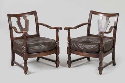 pair of leather armchairs with carved arms and wooden legs