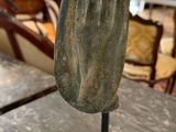 statue of a praying hand on a table in a museum