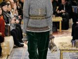 the woman is walking down the runway in a gray sweater and green pants