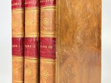 trois vieux livres posés l'un sur l'autre sur une surface blanche