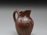 un vieux vase marron orné d'un oiseau, posé sur une table