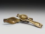 une paire de cuillères en bronze et un repose-cuillère posés sur une surface blanche