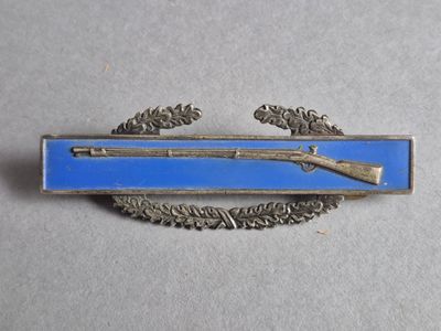un insigne bleu et argent sur lequel figure un fusil