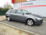 une Audi break grise garée devant un immeuble arborant le logo de Balean Encheres