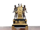 une statue représentant trois personnes tenant une horloge posée sur une table