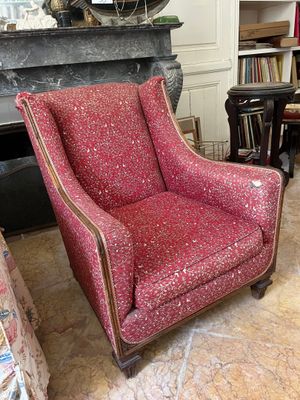 a red chair sitting in a living room next to a fireplace