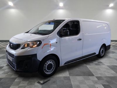 Une camionnette blanche est garée dans une pièce au sol carrelé en damier.