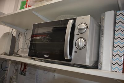 a microwave that is sitting on a shelf in a room