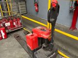 a red and black fork lifter in a warehouse