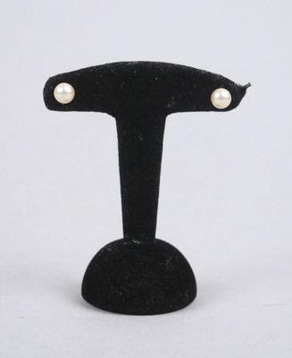 pair of pearl stud earrings on a black velvet stand