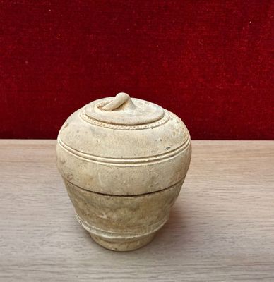 a white vase sitting on a table with a red wall in the background