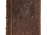 un vieux livre à la couverture brune posé sur une surface blanche