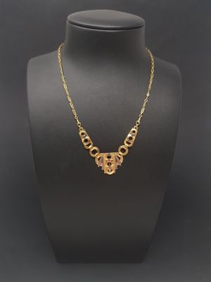 a gold necklace on a mannequin neck with a black background