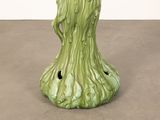 a green vase with a bird on it on a table