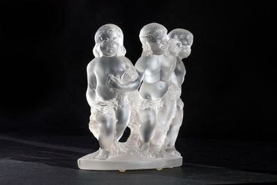 figurines of three children on a marble base against a black background