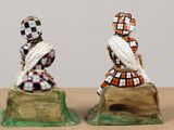 two figurines of a couple sitting on a rock