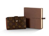 Le portefeuille Louis Vuitton se trouve à côté d'un livre