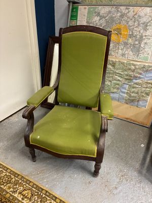a green chair sitting in a room with a map on the wall