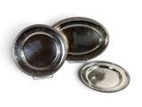 three silver plated dishes on a white surface with one silver plated