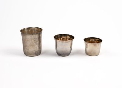 three silver cups sitting next to each other on a white surface