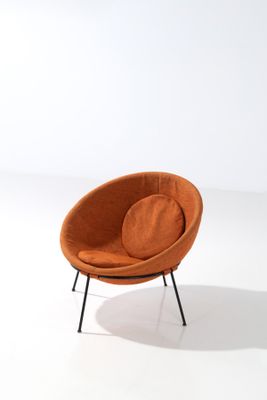 an orange chair with black legs and a round cushion on a white surface
