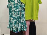 two women ' s shirts hanging on a rack in a clothing store