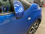 a blue car parked in a parking lot with other cars in the background
