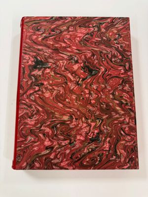 a red and black marbled notebook sitting on top of a white table