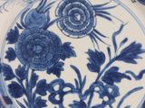 a blue and white plate with flowers and leaves on it